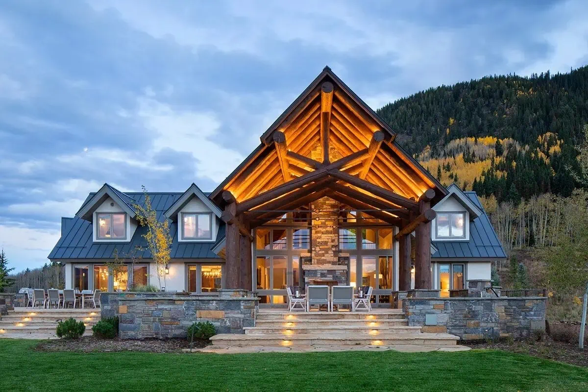Evening view of the log timber home with glowing entry and large windows