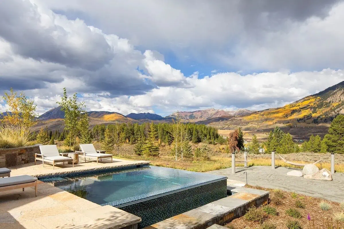 Heated infinity-edge pool surrounded by natural stone patio and loungers