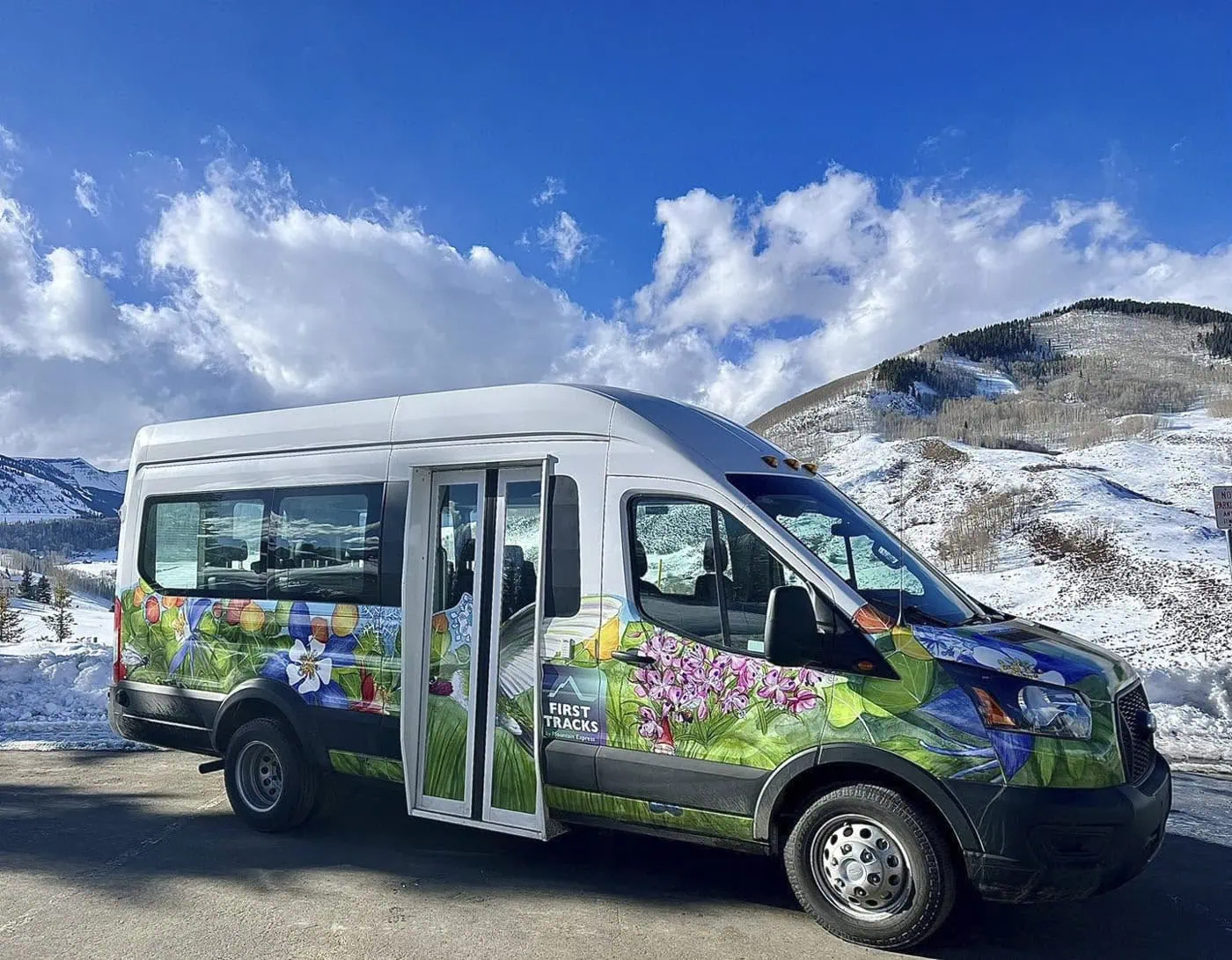 A FirstTracks van, wrapped in wildflowers, in the snow at Mt. Crested Butte